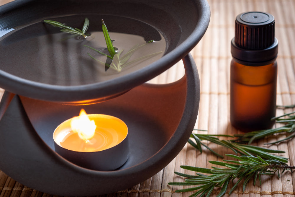 Closeup of oil burner with lighted candle and natural essential oil bottle