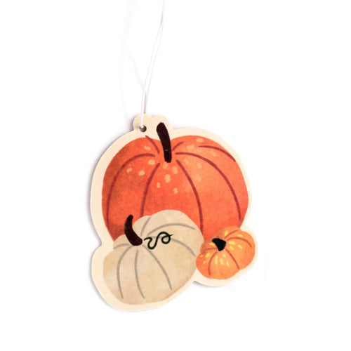 Angled view of an autumn harvest air freshener shaped like three orange and cream pumpkins, with a hanging string.