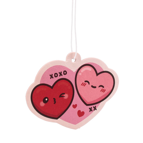 Front view of a pink and red double heart-shaped air freshener, depicting cartoon faces and 'XOXO', 'XX' lettering, hanging by a white string.