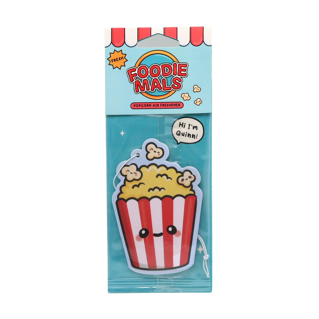 Front view of a popcorn air freshener in its packaging. The air freshener is shaped like a red and white striped popcorn bucket with a yellow popcorn top and a cute cartoon face. It is sealed in clear plastic, with a light blue cardboard header featuring red and white striped awning graphics, FRESH in a yellow starburst, and FOODIEMALS text. A speech bubble inside the packaging reads 'Hi I'm Quinn!', and it includes a white string for hanging.