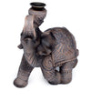 Angled view of a dark brown wood effect elephant backflow incense burner, featuring intricate carved patterns and a metallic dish on its back.