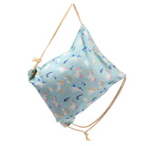 Light blue canvas drawstring bag featuring a unicorn, rainbow, and cloud pattern, shown from an angled perspective with natural rope drawstrings.