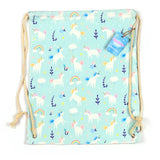 Front view of a light blue canvas drawstring bag featuring a repeating pattern of white unicorns with colourful manes, rainbows, stars, and clouds. It has natural cord drawstrings and a small blue product tag attached.