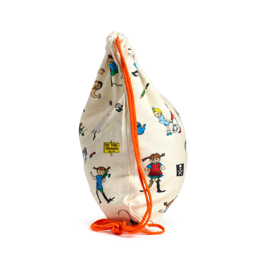 Angled view of a cream canvas drawstring bag with Pippi Longstocking character illustrations and bright orange drawstrings.