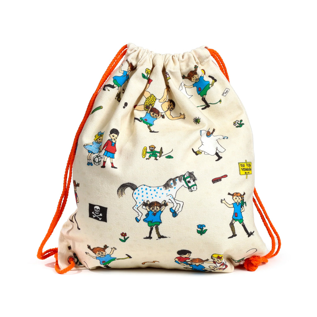 Angled view of a cream canvas drawstring bag, featuring colourful Pippi Longstocking illustrations such as Pippi lifting a spotted horse, with bright orange cord drawstrings.