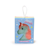 Front view of a unicorn-shaped soap sponge, coloured pink and blue, visible through a unicorn-shaped cut-out window in light blue display packaging with a rainbow stripe top and white hanging loop.
