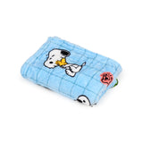 Angled view of a folded light blue plush Peanuts travel blanket, depicting Snoopy and Woodstock characters amidst a subtle grid pattern.