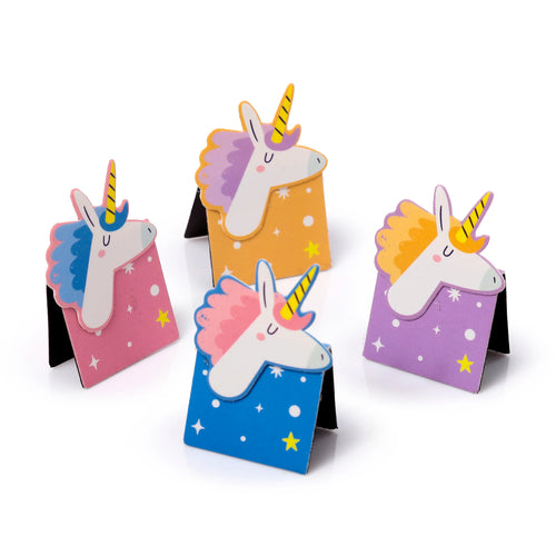 Angled view of a set of four colourful magnetic unicorn bookmarks, each featuring a cartoon unicorn head with a golden horn and mane, on pink, orange, blue, and purple backgrounds decorated with white dots and yellow stars.