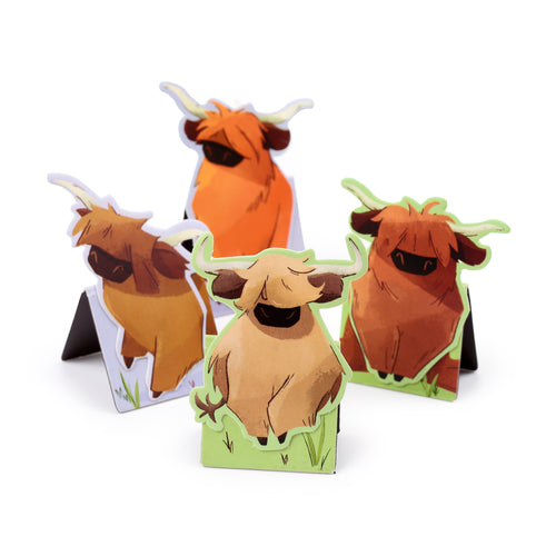 Angled view of four magnetic Highland Coo bookmarks, showing distinct brown and orange coo designs with shaggy hair and horns, standing on green bases.