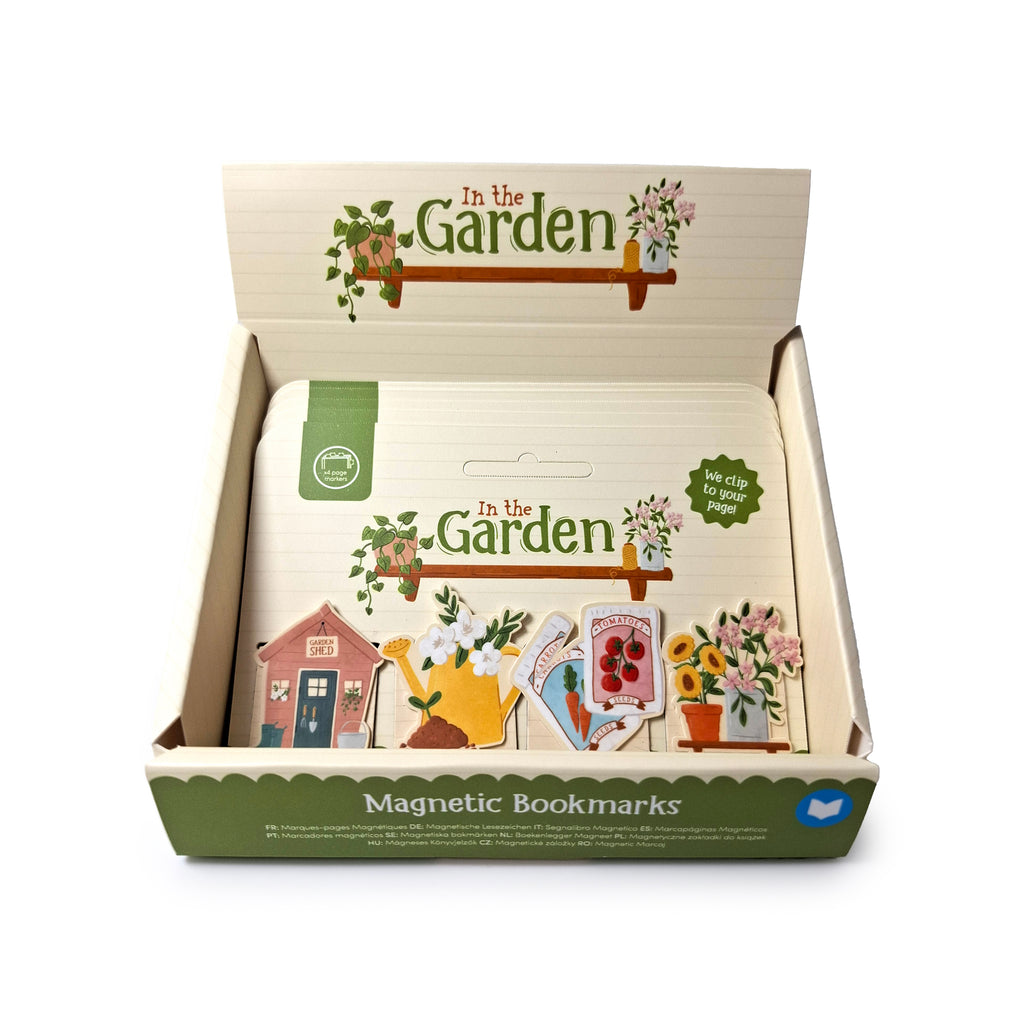 Angled view of an open display box containing a Magnetic Bookmark Set with garden-themed designs, such as a shed, watering can, seed packets, and potted flowers.