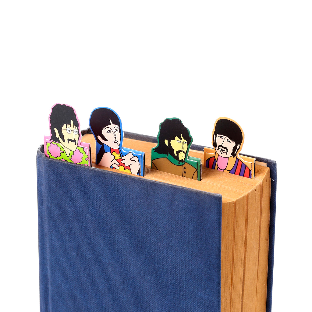 Angled view of The Beatles Yellow Submarine magnetic bookmark set, with four colourful cartoon characters (John, Paul, George, and Ringo) inserted into a dark blue book.