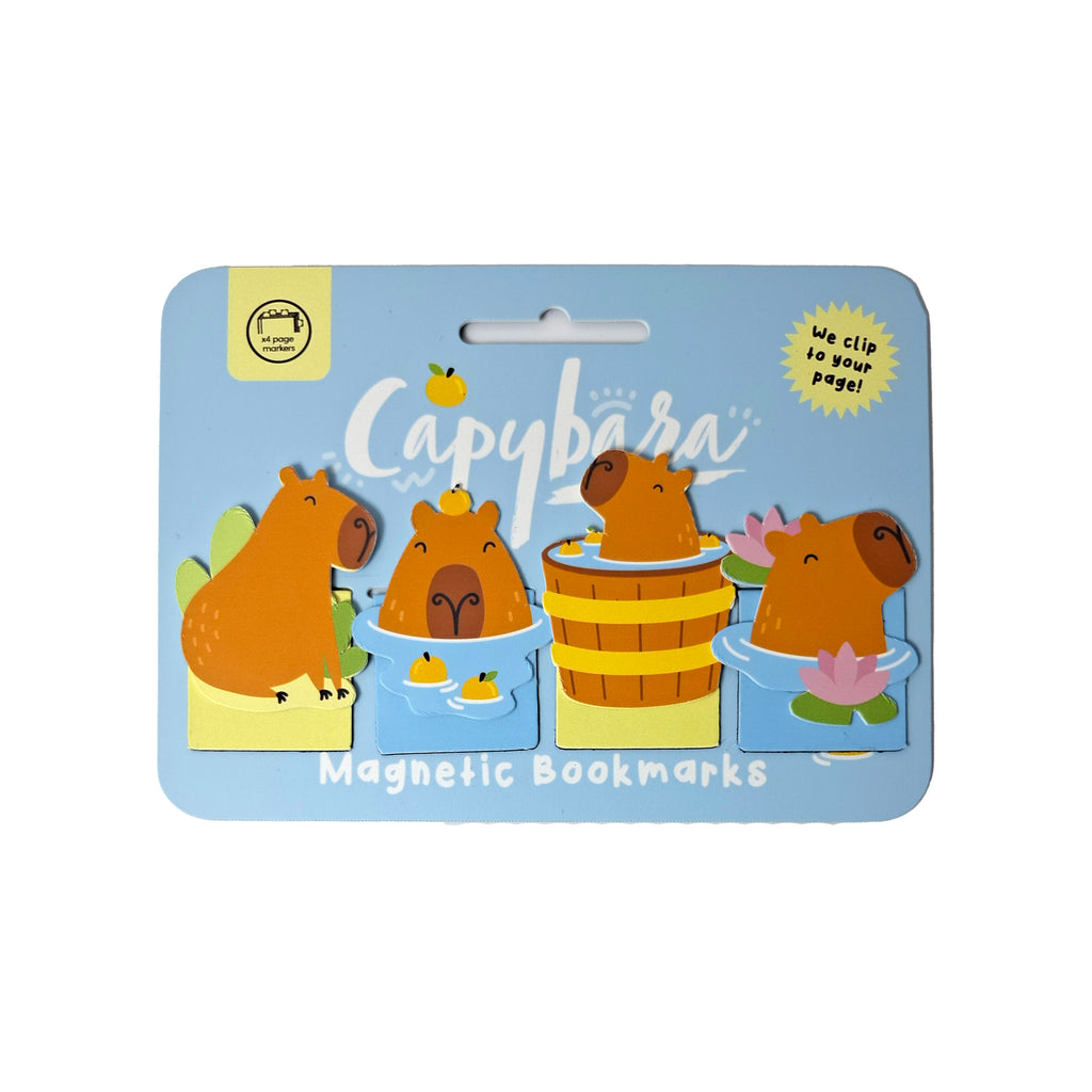 Front view of a magnetic bookmark set, featuring four cute capybara designs on a light blue display card. The capybaras are depicted in various charming scenes, including one with green foliage, another with floating fruit, one inside a wooden barrel, and a fourth surrounded by water lilies.