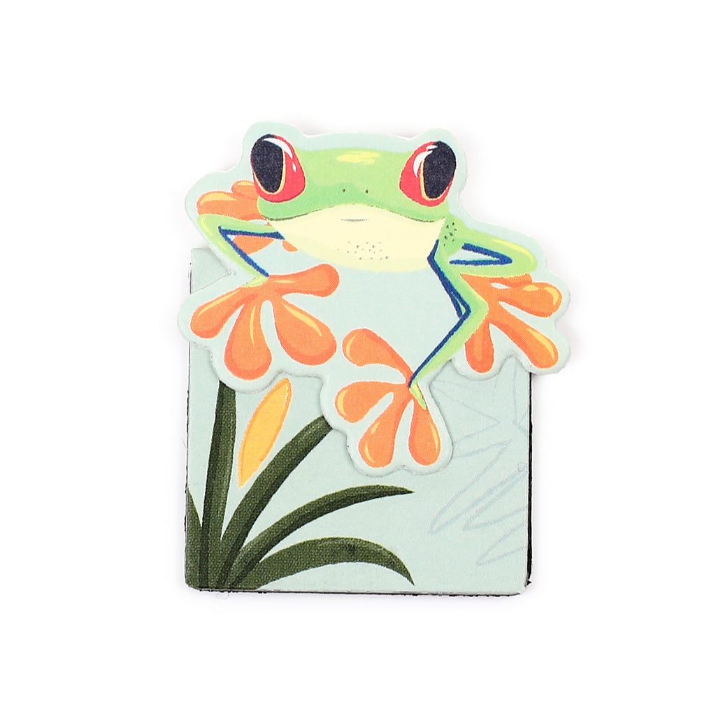 Front view of a tropical frog magnetic bookmark, featuring a green frog with vivid red eyes and orange feet, set against a light blue background with dark green foliage.