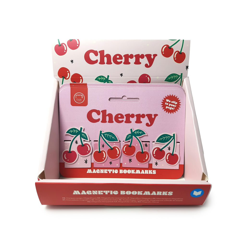 Elevated view of a Cherries Magnetic Bookmark Set in its retail packaging, showing four individual magnetic bookmarks with red cherry designs and green leaves on a pink backing card, inside a white display box.
