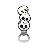 Front view of a PVC bottle opener depicting three stacked black and white skulls, the uppermost skull featuring crossed eyes, attached to a silver-coloured metal opener.