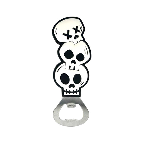 Front view of a PVC bottle opener depicting three stacked black and white skulls, the uppermost skull featuring crossed eyes, attached to a silver-coloured metal opener.
