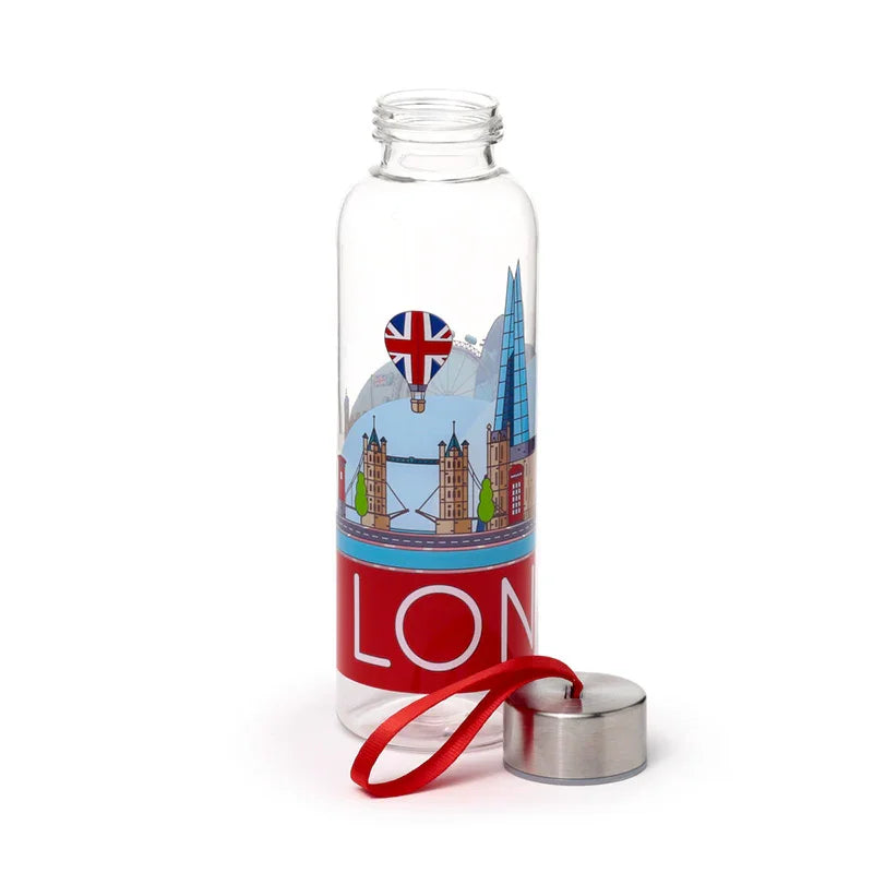 Angled view of a clear glass water bottle, showing a colourful London Icons panorama design featuring Tower Bridge, The Shard, and a Union Jack hot air balloon. A red band with partial white 'LON' text wraps around the base. The metallic lid with a red ribbon handle sits beside the bottle.
