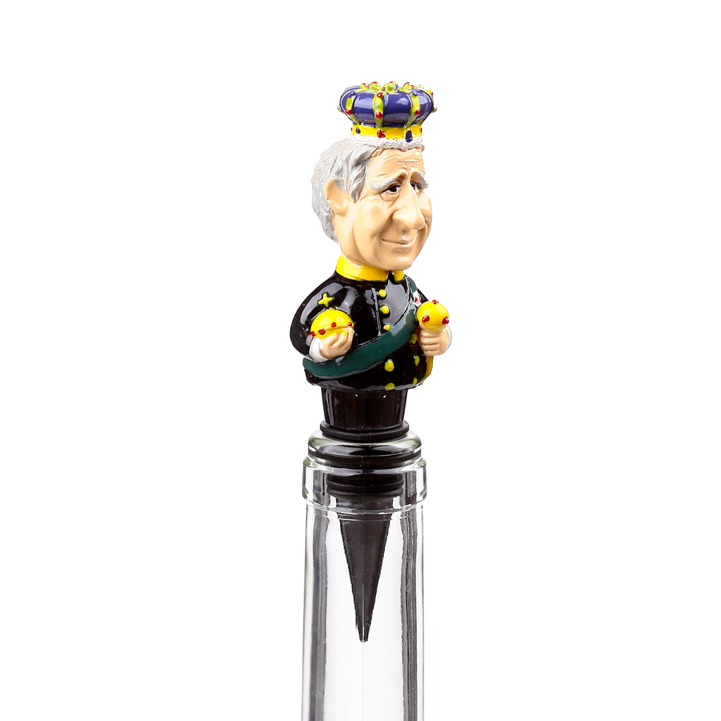 Front view of a novelty bottle stopper featuring a King Charles III caricature wearing a crown and uniform, holding an orb and sceptre, inserted into a clear bottle.