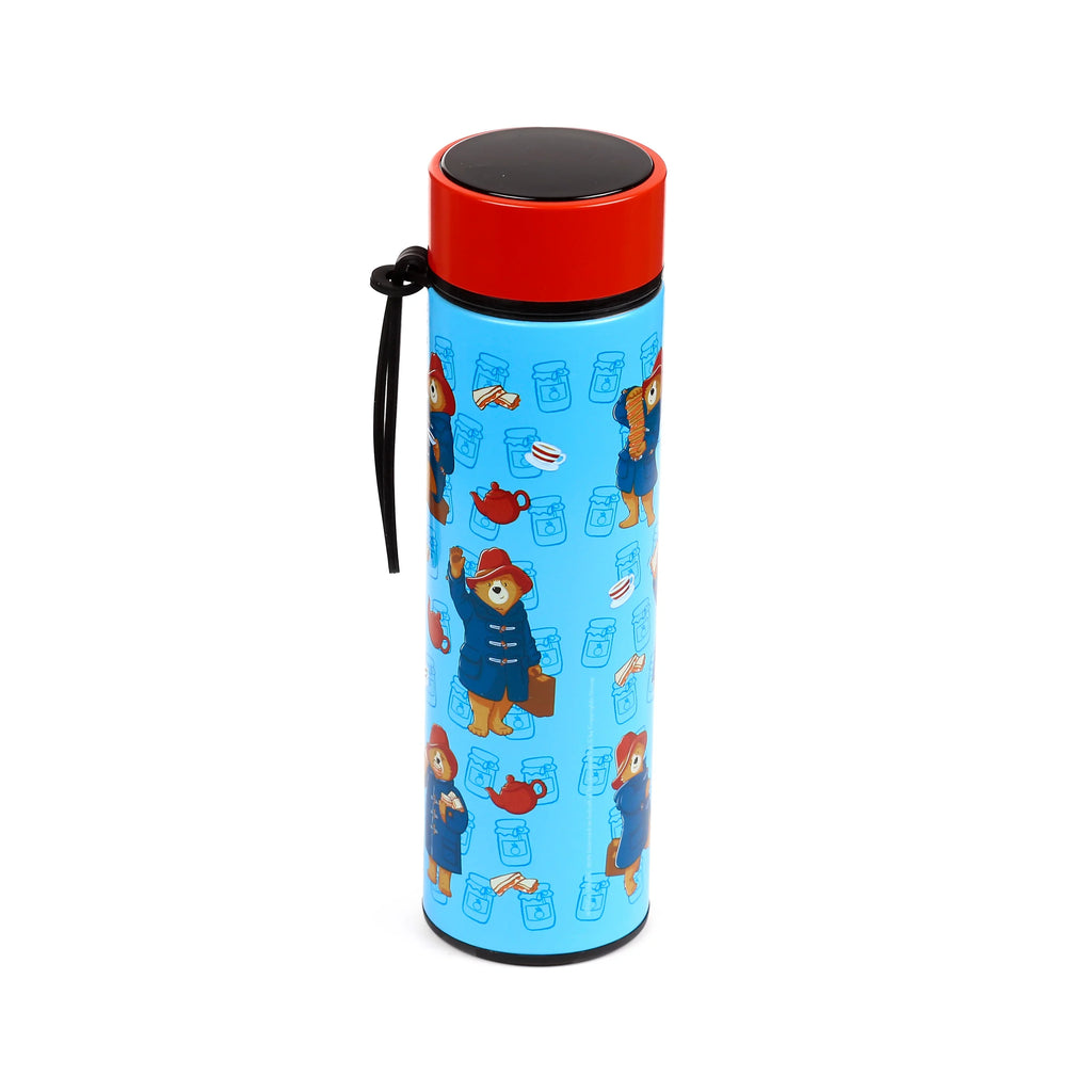 Angled view of a light blue insulated drinks bottle, featuring a pattern of Paddington Bear, jam jars, teapots, and marmalade sandwiches. It has a red lid with a black circular top and a black loop handle.
