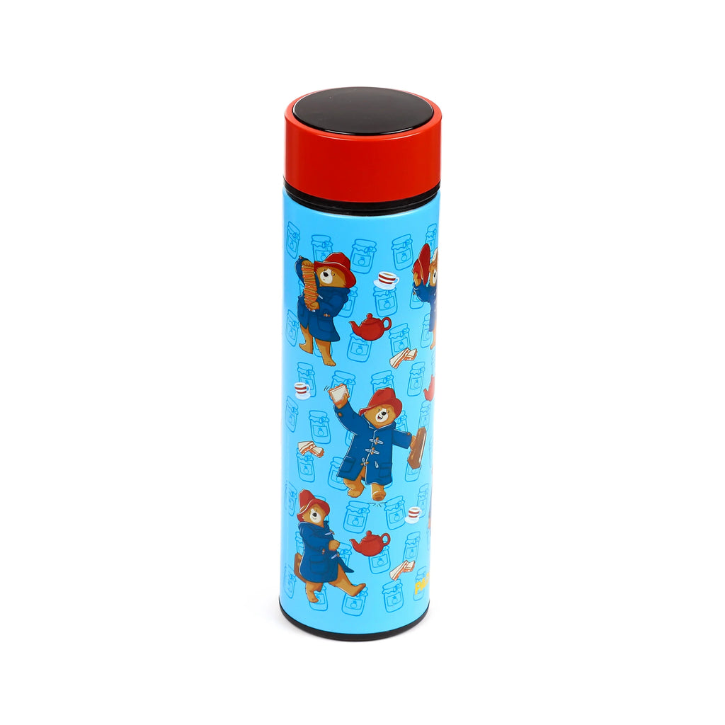 Angled view of a light blue insulated drinks bottle with a red top and black cap, featuring Paddington Bear illustrations surrounded by jam jars and tea motifs.
