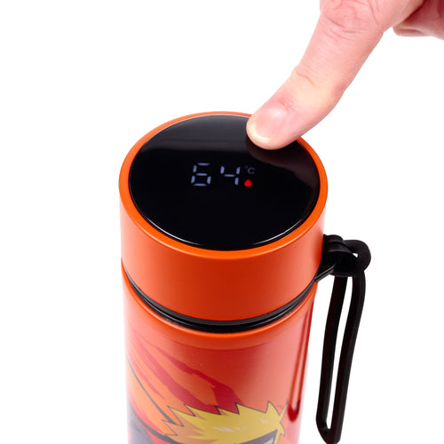 Close-up, overhead view of an orange Naruto insulated flask with a digital thermometer, showing a finger pressing the display which reads 64°C, and a black carry loop.