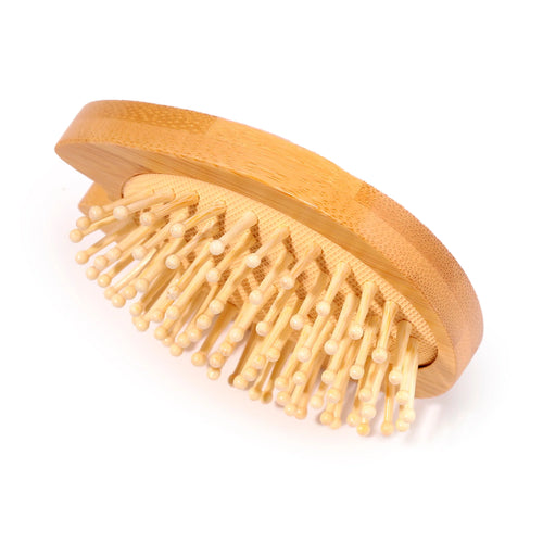 Angled view of an oval bamboo hair brush with a textured surface, light wood-coloured bristles, and rounded tips.