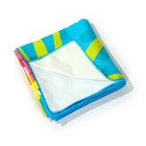 Angled view of a folded microfibre beach towel, showcasing a vibrant turquoise and lime green striped pattern with abstract shapes, and a plain white underside.