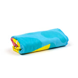 Rolled microfibre beach towel, featuring a vibrant blue outer surface with abstract lighter blue shapes, and flashes of yellow and pink.
