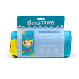 Front view of a rolled microfibre beach towel in retail packaging, displaying a turquoise label with a 'Vacation Vibes' unicorn graphic. Visible towel sections show yellow, pink, and blue colours.