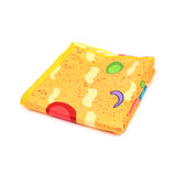 Angled view of a folded yellow beach towel with an abstract pattern of red, green, and purple shapes, and speckled orange details, finished with bright yellow stitching.