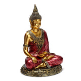 Front view of a red and gold Thai Buddha figurine, seated in contemplation with intricate golden patterns on its robes and decorative base.