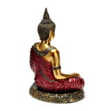 Rear view of a red and gold Thai Buddha figurine, seated in a meditative pose, with intricate details on its robe and ornate base.