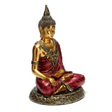 Angled view of a red and gold Thai Buddha figurine seated in contemplation, featuring ornate robes and a patterned base.