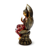Red and gold Thai Buddha figurine, angled view, seated on a lotus base, showing a raised hand and profile.