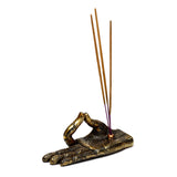 Angled view of an antique gold-coloured Buddha hand incense holder, intricately decorated with henna-style patterns, holding three light brown incense sticks.