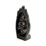 Angled view of a decorative black hand-shaped Thai Buddha figurine, featuring a carved silver and metallic black lotus design within its palm.