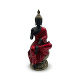 Front view of a black Thai Buddha figurine, dressed in a shiny red robe with gold topknot and ornate base, seated with one hand raised.