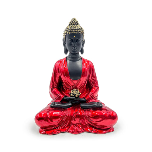 Front view of a decorative Thai Buddha figurine, sitting in a meditative pose with shiny red robes, matte black skin, textured gold hair, and holding a golden lotus flower.