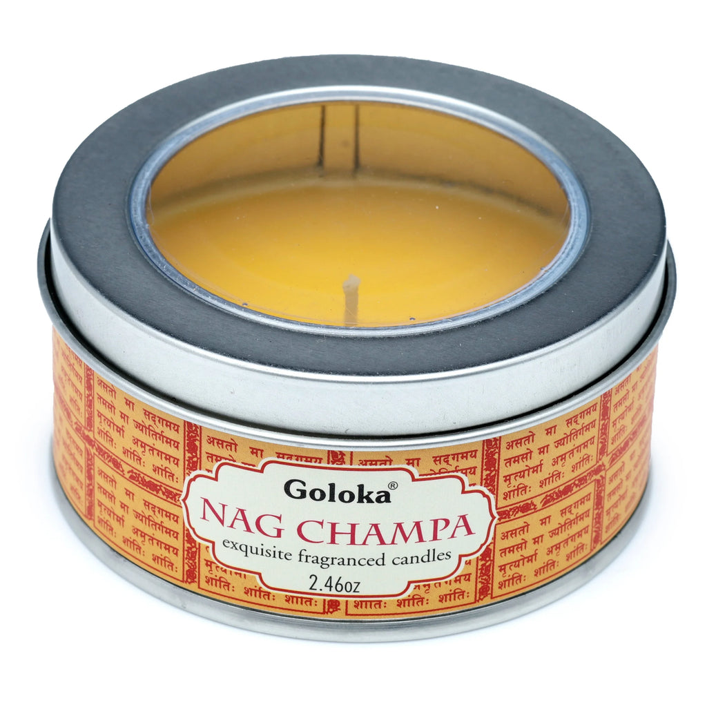 Angled view of a silver-coloured cylindrical Goloka Nag Champa wax candle tin with a clear lid, revealing golden-yellow wax and a white wick. The side label is pale orange with red script and 'Goloka NAG CHAMPA' text.