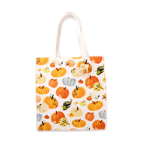 Front view of a white shopping tote bag, displaying an autumn harvest print of various orange, yellow, cream, pale blue, and striped gourds and pumpkins. It has light-coloured fabric handles and a 'Autumn Harvest Cotton Bag' hang tag.