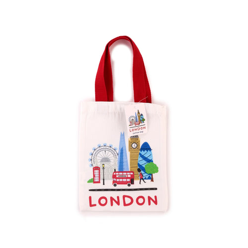 Front view of a small cream tote shopping bag with red handles, featuring a colourful illustration of London landmarks: the London Eye, Big Ben, The Shard, The Gherkin, a red telephone box, and a red double-decker bus, alongside a Queen's Guard figure, and 'LONDON' text.