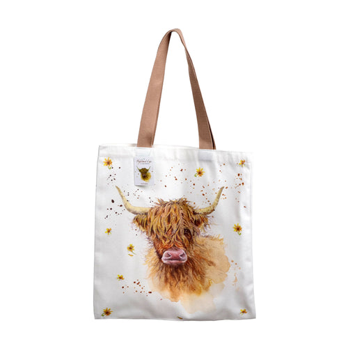 Front view of a white shopping tote bag with brown handles, featuring Jan Pashley Highland Coo artwork. The design depicts a shaggy ginger coo surrounded by yellow flowers and brown splatters.