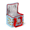 Angled view of a light blue cool bag with red handles and zipper trim, open to reveal its crinkled silver insulated interior. The bag features a playful pattern of cartoon fast food characters.