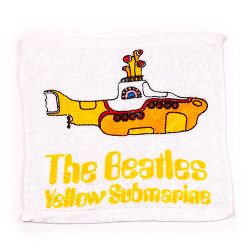 Overhead view of a white travel towel featuring a yellow submarine design and 'The Beatles Yellow Submarine' text.