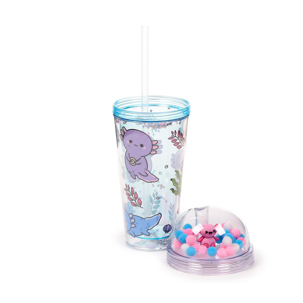 Angled view of a clear double-walled cup with a light blue rim, decorated with purple and blue axolotl characters, seaweed, and glitter stars. A clear straw is inside the cup. The detached, clear dome lid is shown beside it, containing pink, blue, and white pom-poms and a pink axolotl charm.