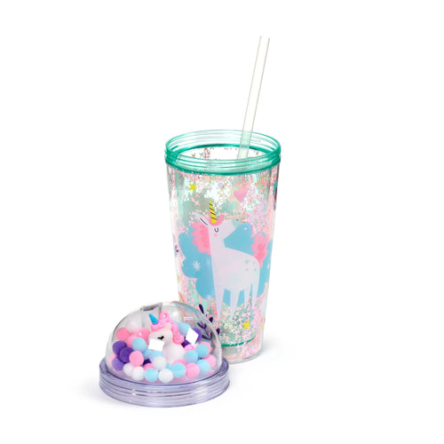 Angled view of a clear double walled cup with a unicorn graphic, internal glitter stars, and a teal rim, alongside a separate dome lid holding a white unicorn charm and colourful pom-poms; a white straw is included.
