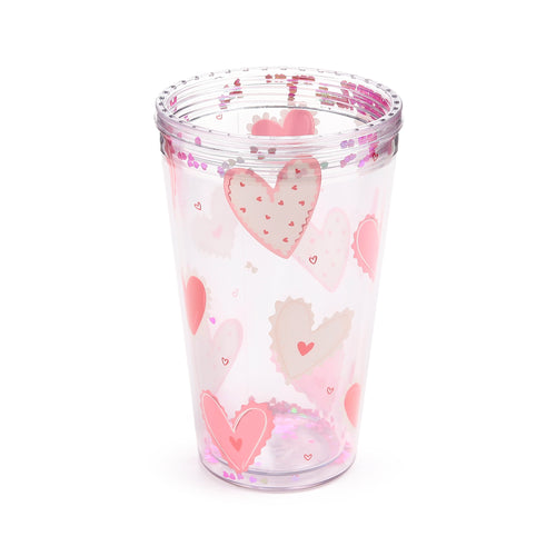 Angled view of a clear double-walled cup featuring pink heart patterns and floating pink heart-shaped glitter.