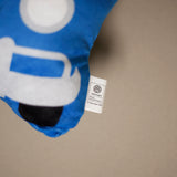 Close-up showing the white official Volkswagen product tag on a blue plush shaped cushion.