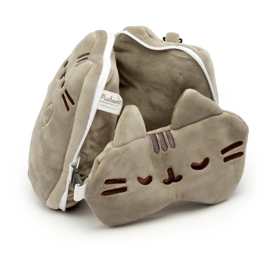 Angled view of a beige plush Pusheen cat-shaped travel pillow, zipped into a compact form, with a matching Pusheen cat-face eye mask emerging, on a white background.