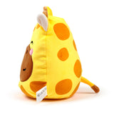 Angled view of Raffi the giraffe plush toy, soft and yellow with brown spots, a brown snout, closed eyes, pink cheek blushes, and small ears. A brown-tipped tail and a white fabric tag are visible on the side.